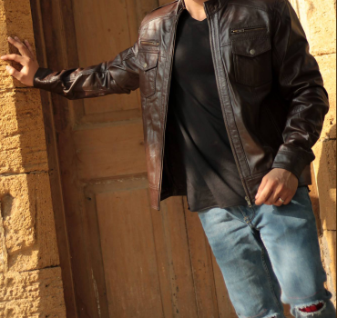 Man wearing a brown leather biker jacket with asymmetrical zip and quilted details.