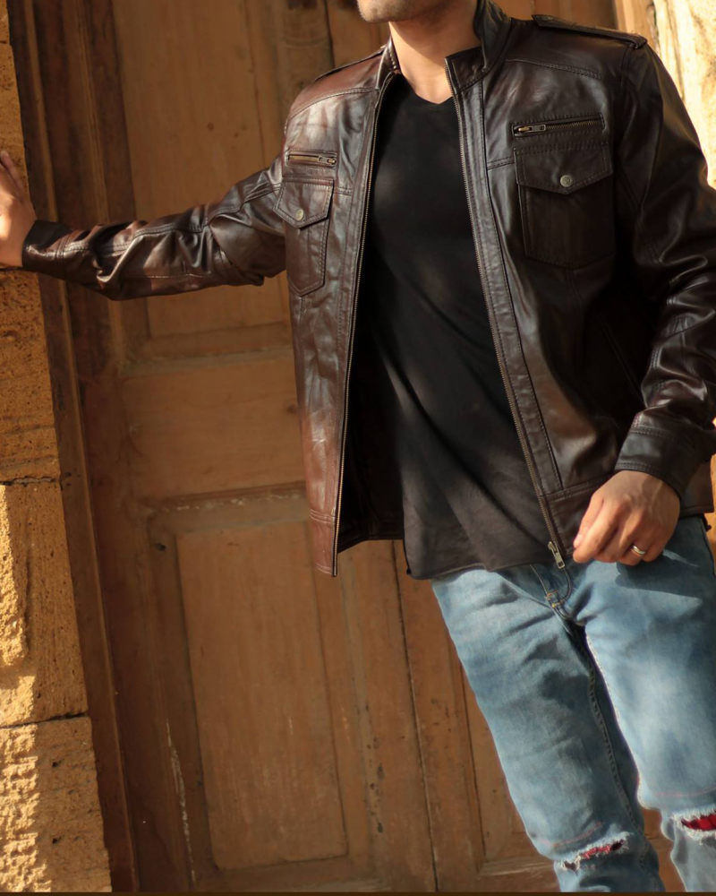 Man wearing a brown leather biker jacket with asymmetrical zip and quilted details.