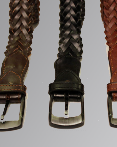 Leather belt with embossed cross design and metal buckle on plain background